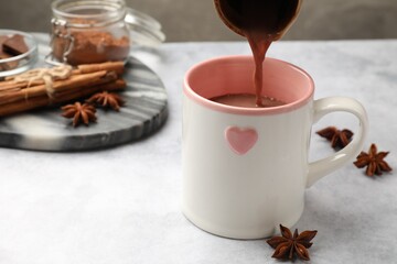 Sticker - Pouring tasty hot chocolate into cup at light table, closeup. Space for text