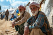 © ebhanu - Two old refugee men in a refugee camp border. World Refugee Day.