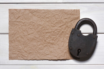 Wall Mural - old padlock and blank crumpled paper sheet page on the wooden desk table background. top view. secre