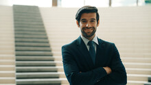 Smart Caucasian Business Man Standing With Folded Arm While Looking At Camera. Professional Handsome Project Manager Pose At Camera While Smiling With Confident With Blurred Background. Exultant.