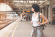 Happy woman with a backpack while at the train station and the train is arriving. Enjoying travel concept