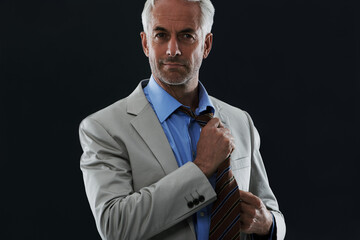 Poster - Fashion, portrait and businessman with tie in studio with classy, elegant and corporate suit. Style, serious and professional mature male person undressing with outfit by dark black background.