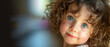 A child with bright blue eyes and curly hair offers a look of innocence and wonder