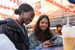 Young women checking phone while dining outdoors in Chinatown