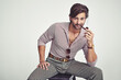 © YATrainer/peopleimages.com - Fashion, man and portrait or smoking in studio with retro pipe, hipster outfit and confidence on chair. Model, person and face with 70s style, mock up space and calm expression with white background