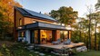 Eco friendly contemporary passive house with light inside and solar panels and terrace in Indian summer with photovoltaic system on the roof against forest landscape