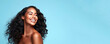 Portrait of a young smiling black woman. Skin care beauty, skincare cosmetics. Isolated over blue background. Copy space.
