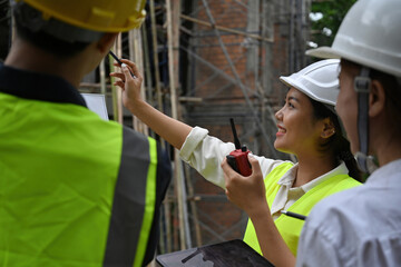 Close-up of a female engineer pointing at construction building, meeting of a worker team, Quality inspection, Working plan, and Building design project