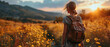 Back view of a solitary traveler with a leather backpack gazing at a sunset over a golden flower field