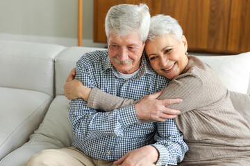 Senior adult mature couple hugging at home. Mid age old husband and wife embracing with tenderness love enjoying sweet bonding wellbeing. Grandmother grandfather together. Family moment love and care