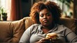 An overweight black african woman relaxing on the sofa and eating a sandwich from Generative AI