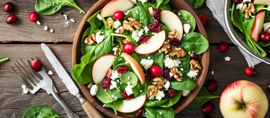 Poster - A delicious salad made with spinach, apples, cranberries, walnuts, and cheese, served in a rustic wooden bowl.