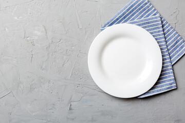 Poster - Top view on colored background empty round white plate on tablecloth for food. Empty dish on napkin with space for your design