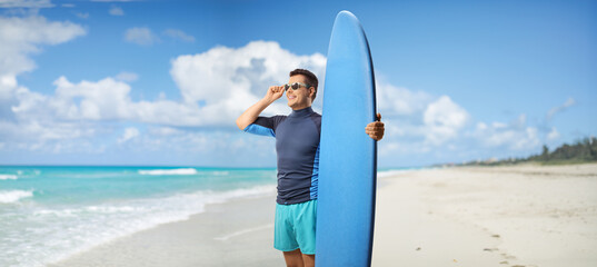 Sticker - Man with sunglasses and a surfing board standing on a beach in Cuba