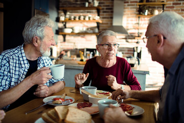 Wall Mural - Smiling senior people having breakfast together at home