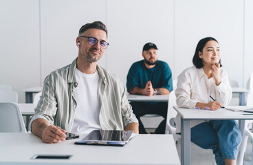 Fototapete - Portrait of happy Caucasian businessman in bluetooth headphones smiling at camera during collaboration time in office interior,successful male employee in optical eyewear for provide vision correction