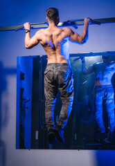 Wall Mural - Young muscular man doing pull ups in gym