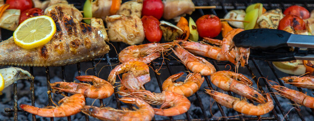 Wall Mural - Shrimp, vegetables and fish are fried on a barbecue. Selective focus.