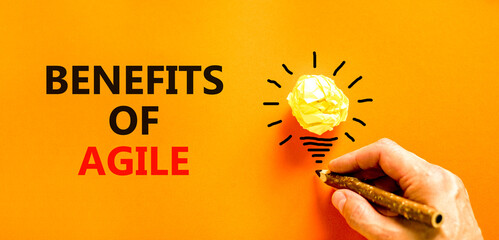 Benefits of agile symbol. Concept words Benefits of agile on beautiful orange paper. Beautiful orange background. Light bulb icon. Businessman hand. Business benefits of agile concept. Copy space.