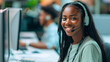 Cheerful young woman wearing a headset and working at a computer, in a customer service or call center environment.