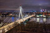 Fototapeta Miasto - Swietokrzyski Bridge over the Vistula River with a panoramic view of the center of Warsaw at night. Poland