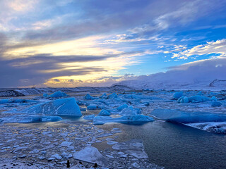 Icebergs swimming at the famous glacier lagoon around Vatnajokull National Park during winter around sunset time 