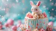 Pastel blue Easter cake with a rabbit topper and pink candy decorations.