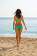 © Tijana - Attractive brunette in a green bikini, relaxing on a sandy beach by the sea.Beautiful young brunette woman in a green bikini enjoying summer vacation at the seaside. She is walking, posing, relaxing.