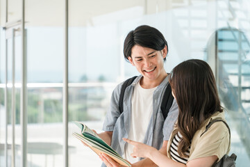 教科書を持つ学生・大学生の男女（キャンパスライフ・恋人・カップル）
