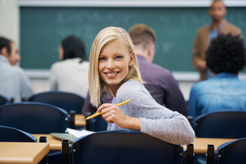 Wall Mural - University student, portrait and smile at classroom desk in London for english lecture, education or scholarship. Female person, face and pen at academy with professor for teaching, lesson or exam