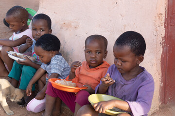 group of village african children eating in the yard, famine and malnutrition ngo solving world prob