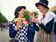 Clown, people and outdoor at festival, carnival or costume for event or concert in park. Happy, women and smile in funny props, clothes and dress up for culture, party in summer or holiday bubbles