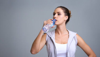 Poster - Woman, fitness and drinking water for hydration or natural sustainability on a gray studio background. Face of thirsty female person or athlete with mineral drink in rest, break or recovery on mockup