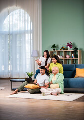 Wall Mural - Happy indian family using laptop while sitting on sofa at home.