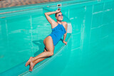 Fototapeta Tęcza - Bikini-clad woman enjoys poolside relaxation. Poolside ambiance. Capturing woman's relaxed time near pool.