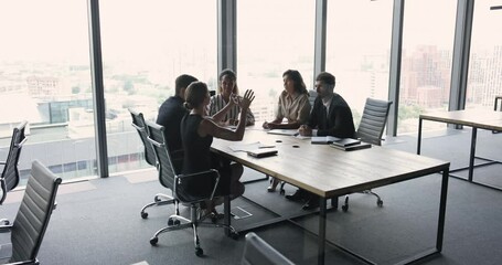 Poster - Wide shot of diverse business team talking at large meeting table in contemporary modern office space with large window and city view. Office colleagues brainstorming on project