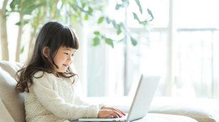 Young girl sit on white sofa at home. Child looking at laptop screen. Happy kid watch fun video on computer, playing game, or learning online. Distance Internet education concept. Virtual class study.