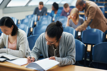 Wall Mural - Students, university and writing exam in classroom, information and notes for studying. People, books and knowledge in education for learning, problem solving and ideas for solution in assessment