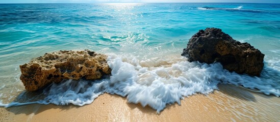 Wall Mural - The azure waves crash on the rocky beach, creating a mesmerizing natural landscape along the fluid and expansive oceanic horizon.