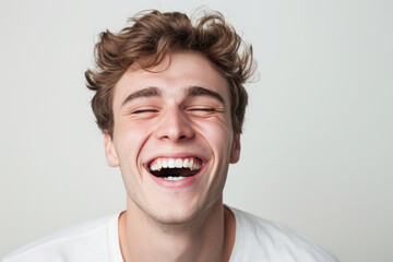 Wall Mural - Joyful young man laughing against plain background. Human emotion and expression.