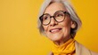 © iuricazac - Smiling older woman with gray hair and glasses wearing a yellow scarf against a yellow background.