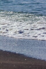 Poster - Vertical shot of a beach during the daytime with the waves washing up to the sandy shoreline