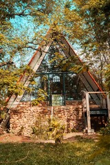 Poster - a triangle house is seen through the woods in this photo