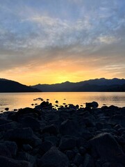 Canvas Print - Stunning lake with a beautiful orange sunset over the jagged mountain range in the background