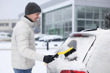 Canvas Print - Man cleaning snow from car window outdoors