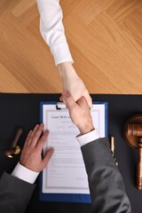 Wall Mural - Notary shaking hands with client at wooden table, top view