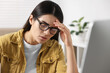 © New Africa - Young woman suffering from headache at workplace indoors