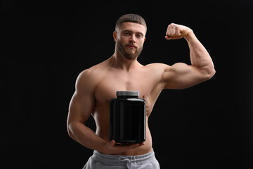 Canvas Print - Young man with muscular body holding jar of protein powder on black background