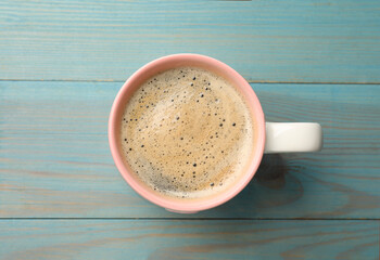 Wall Mural - Cup of aromatic coffee on light blue wooden table, top view