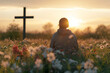 back view of woman sitting on the flowers meadow and looking on cross. Easter tranquil scene